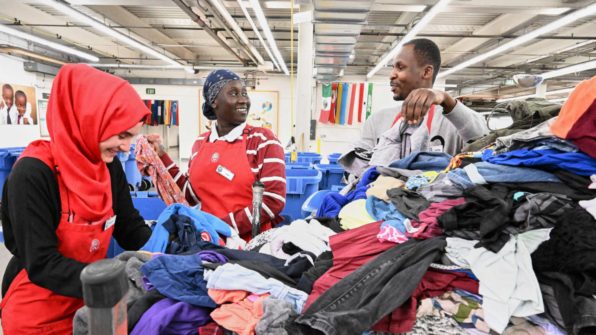 Three DI associates laugh as they talk and sort donated clothing at the LDS Humanitarian Center.